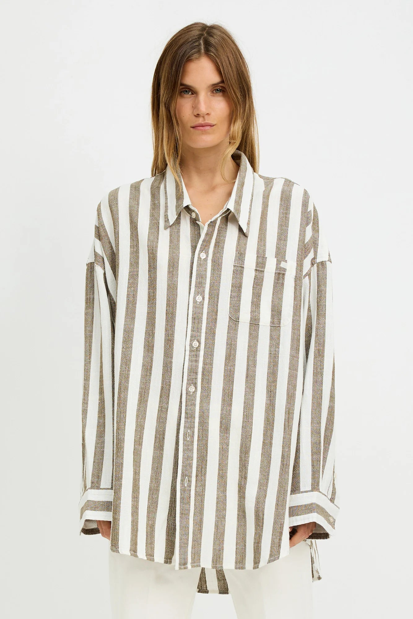 A person with straight, light brown hair models the Denimist BUTTON FRONT SHIRT STRIPE, a relaxed fit long-sleeve shirt with jumbo beige and white stripes, standing against a plain white background.