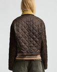 A person with blonde hair, seen from behind, wears the Denimist Cropped Quilted Jacket with a corduroy collar, a striped shirt, and olive green shorts against a plain light background.