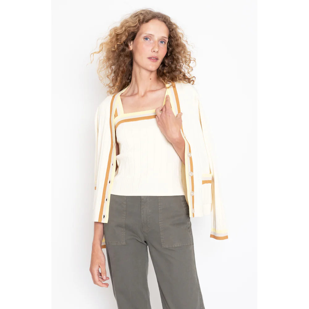 A person with wavy, light brown hair wears The Dede Cream/Hazelnut by Kule over a matching top. They pair it seamlessly with olive green pants, embodying the perfect spring/summer layer against a plain white background.