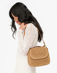 Clare Vivier Turnlock Louis Top Handle tote in white, styled with a long white dress for an elegant look.