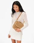 Clare Vivier Turnlock Louis top handle bag styled with a white crochet dress and purple necklace for a fresh, airy look.