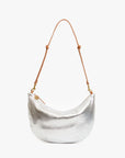 The Clare Vivier Lune is a crescent-shaped metallic silver handbag featuring a textured surface and a brown chrome-tanned leather shoulder strap, displayed against a plain white background.
