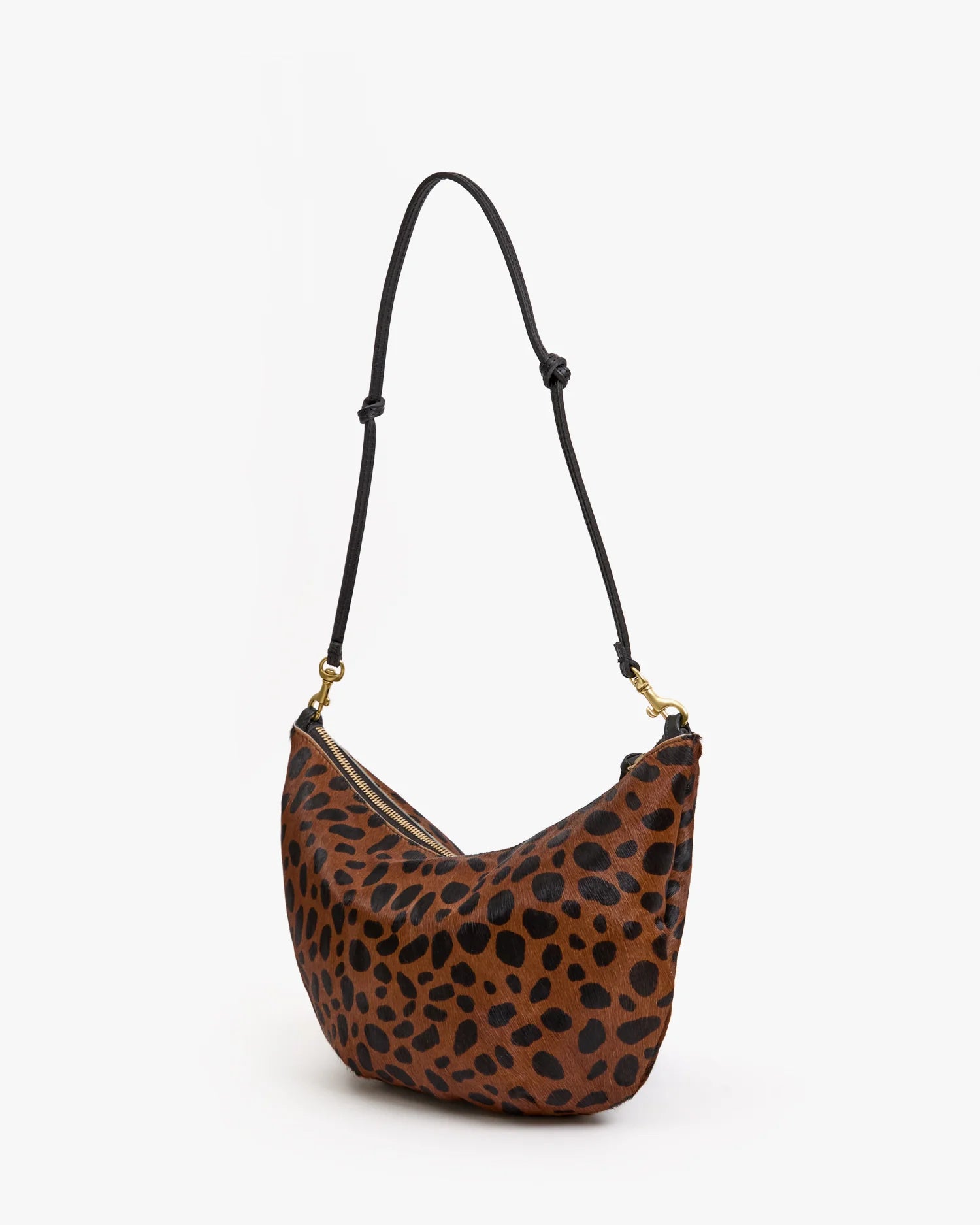 The Clare Vivier F25-Lune is a brown hair-on leather shoulder bag with a black leopard print, adjustable black strap, and gold hardware, shown against a white background.