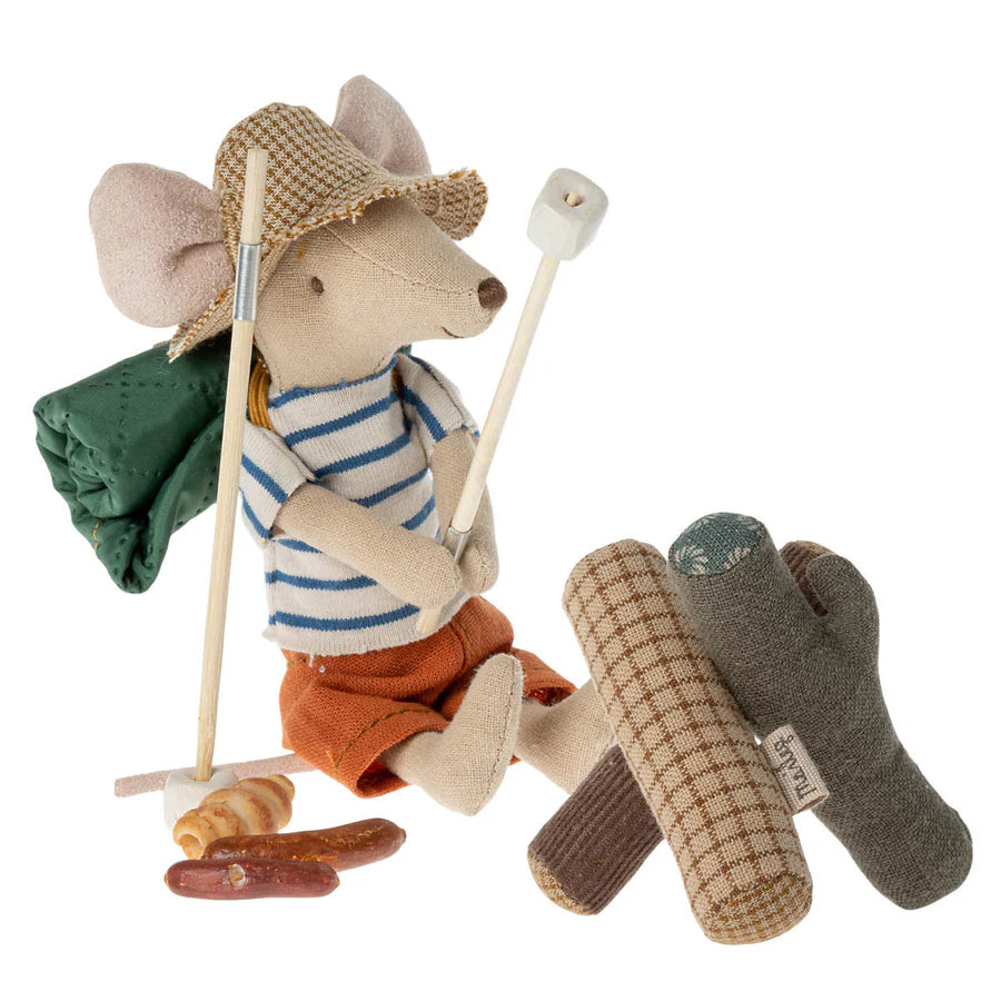 A Maileg mouse from the Maileg Bonfire Set, ready for adventure in a straw hat and striped shirt, camps by a fabric campfire with marshmallows, a green backpack, and play food accessories from Maileg.