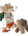 A Maileg mouse from the Maileg Bonfire Set, ready for adventure in a straw hat and striped shirt, camps by a fabric campfire with marshmallows, a green backpack, and play food accessories from Maileg.