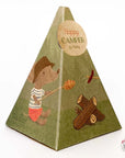 Pyramid-shaped box featuring a hiking mouse doll in a hat and shorts roasting marshmallows by the campfire. The circular label reads "Happy CAMPER by Mallory." The Maileg Bonfire Set by Maileg is perfect for mouse camping adventures.