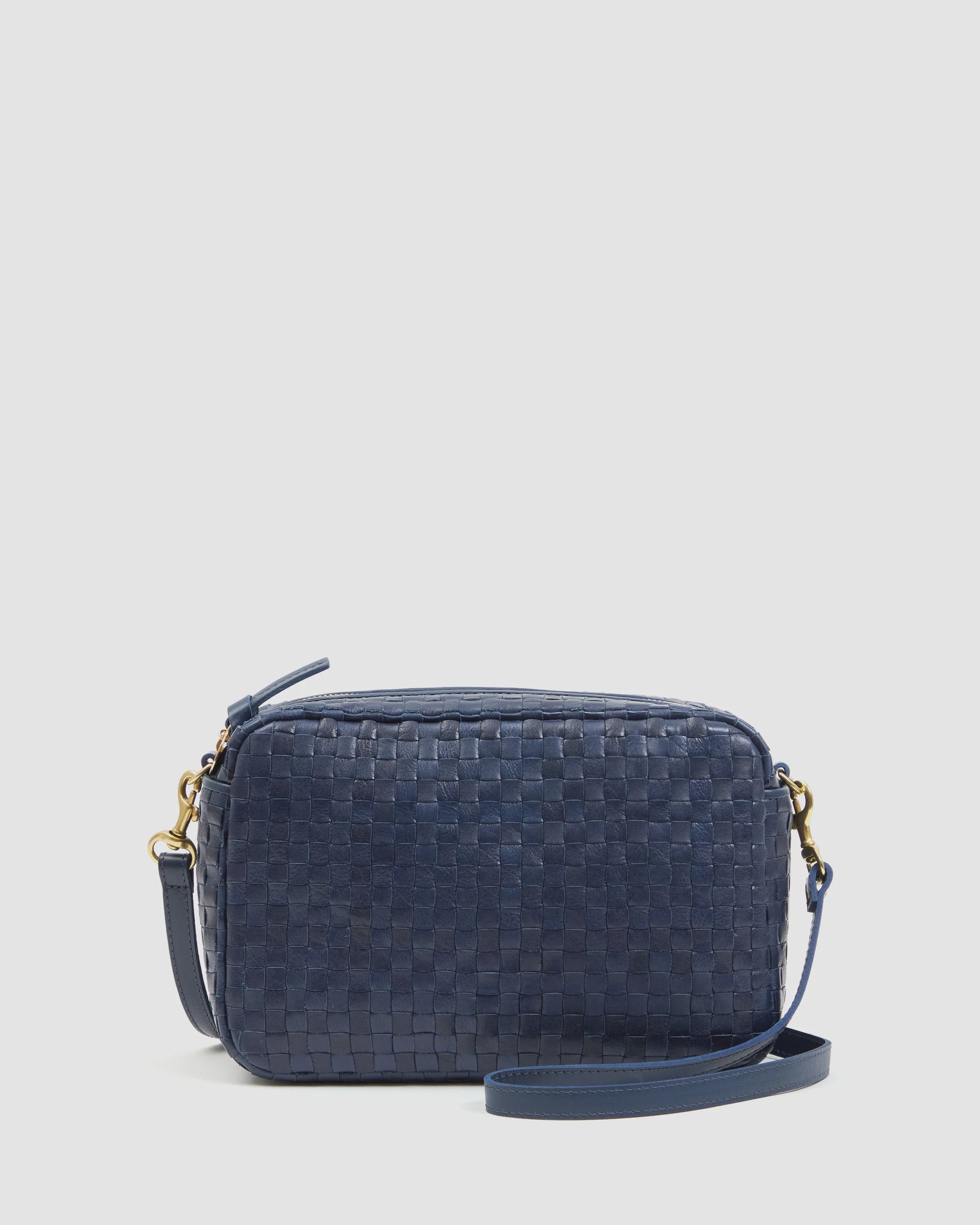The Clare Vivier Marisol is a small rectangular handwoven leather bag in dark blue with gold-tone hardware and a matching adjustable crossbody strap, shown against a plain light background.