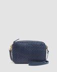 The Clare Vivier Marisol is a small rectangular handwoven leather bag in dark blue with gold-tone hardware and a matching adjustable crossbody strap, shown against a plain light background.