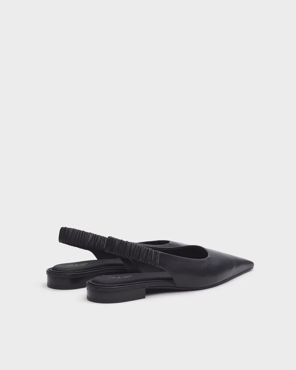 The Rag & Bone mercer slingback flat features black pointed-toe leather, low heels, elastic ruched straps, and a cushioned footbed, shown on a plain light background.