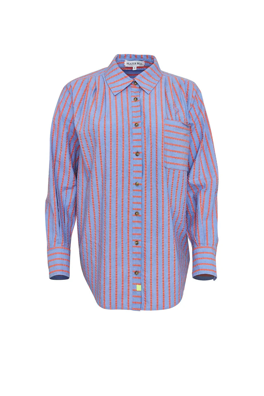 The relaxed fit Miles Shirt by Hunter Bell NYC showcases blue and red beach stripes, a collar, long sleeves, a button front, and a practical left chest pocket. The shirt is elegantly displayed against a white background.