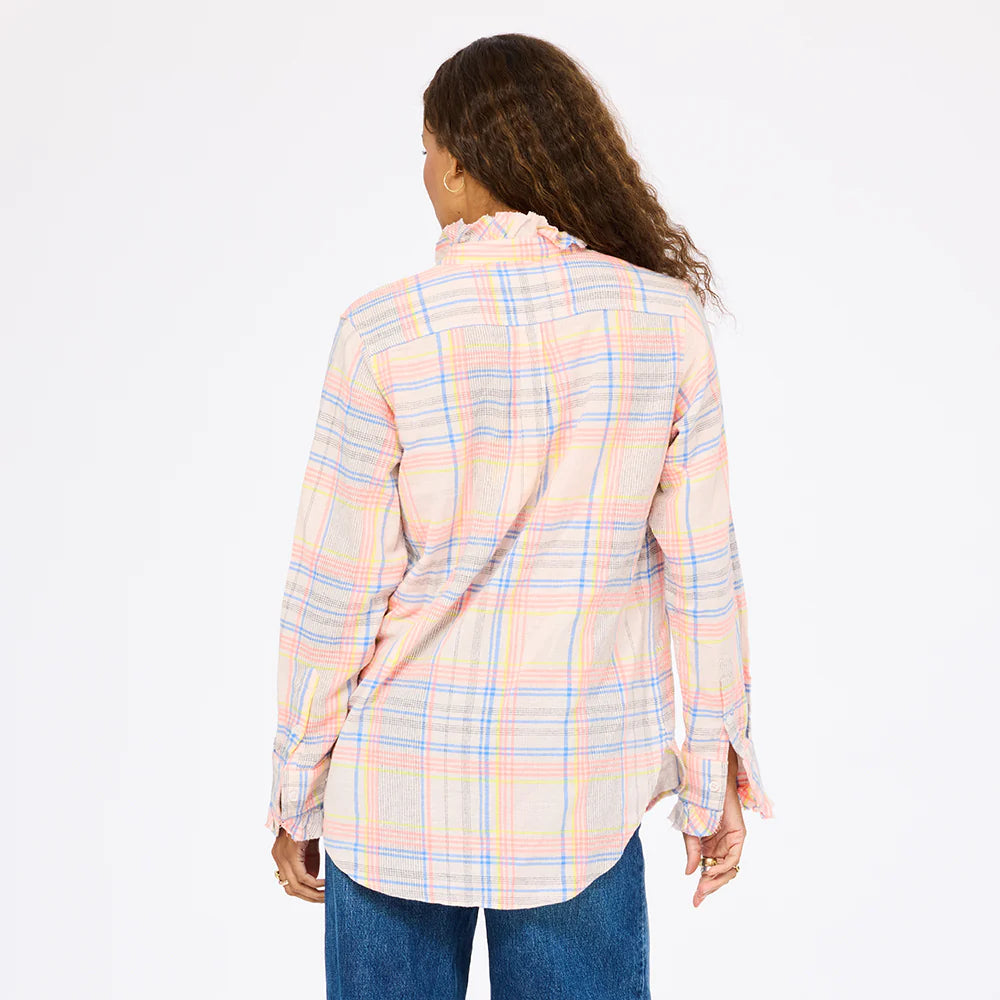 A person with long, curly hair is shown from the back wearing the Kerri Rosenthal Molly Shirt—a loose-fitting, long-sleeve plaid flannel—paired with blue jeans, against a plain white background.