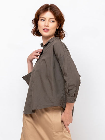 Monday12 Zoe Shirt in Dark Olive styled with beige pants, casual look, model gazing sideways, hand at collar.