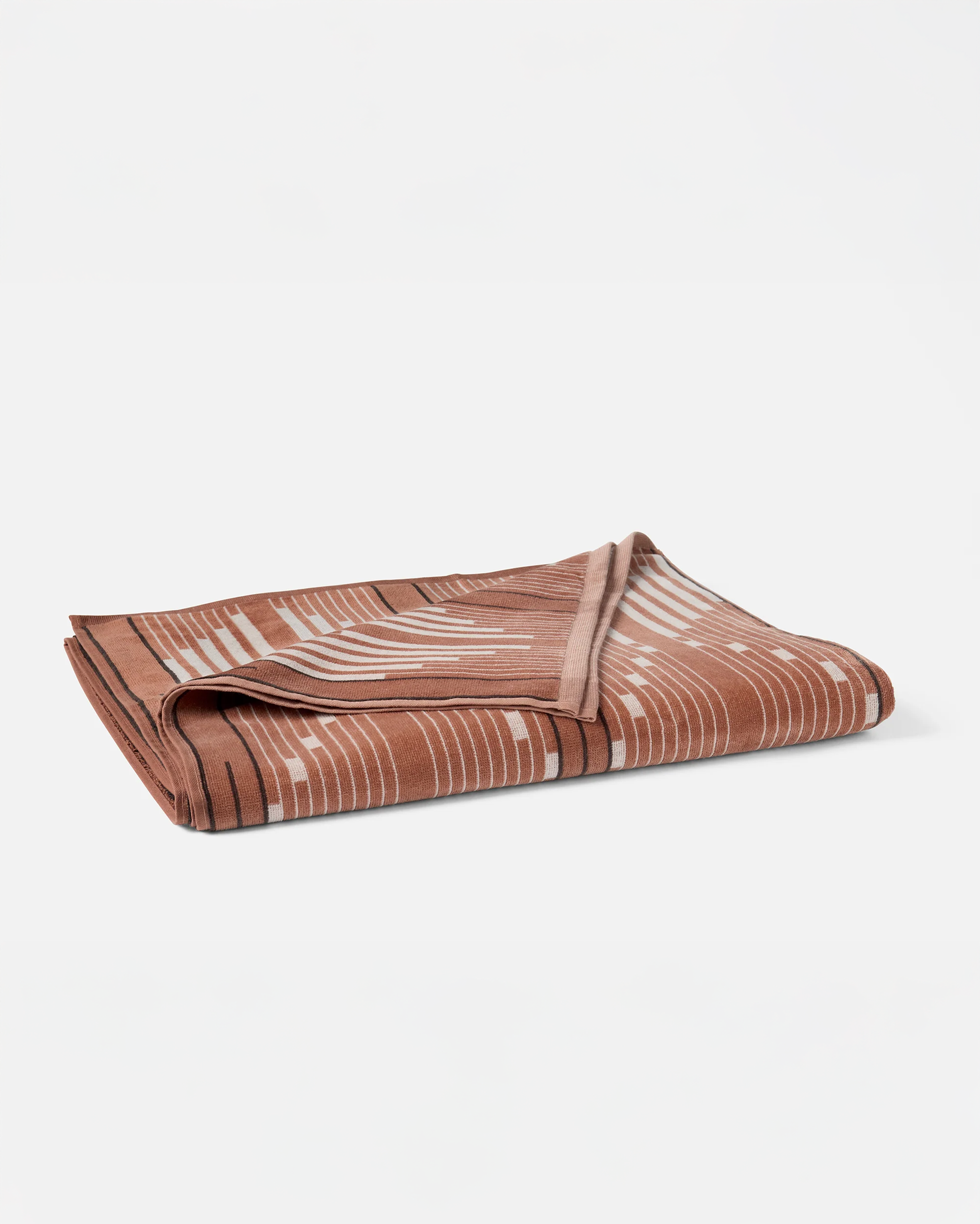 The Morelia Beach Towel by Coyuchi Inc, featuring a white and black abstract line pattern on a brown velour terry weave, is displayed on a plain white background.