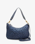 The Moyen Messenger by Clare Vivier is a navy blue nappa woven leather handbag featuring a short strap and gold hardware. Set against a plain background, this zip-top crescent bag highlights its intricate weaving, combining elegance with versatility.