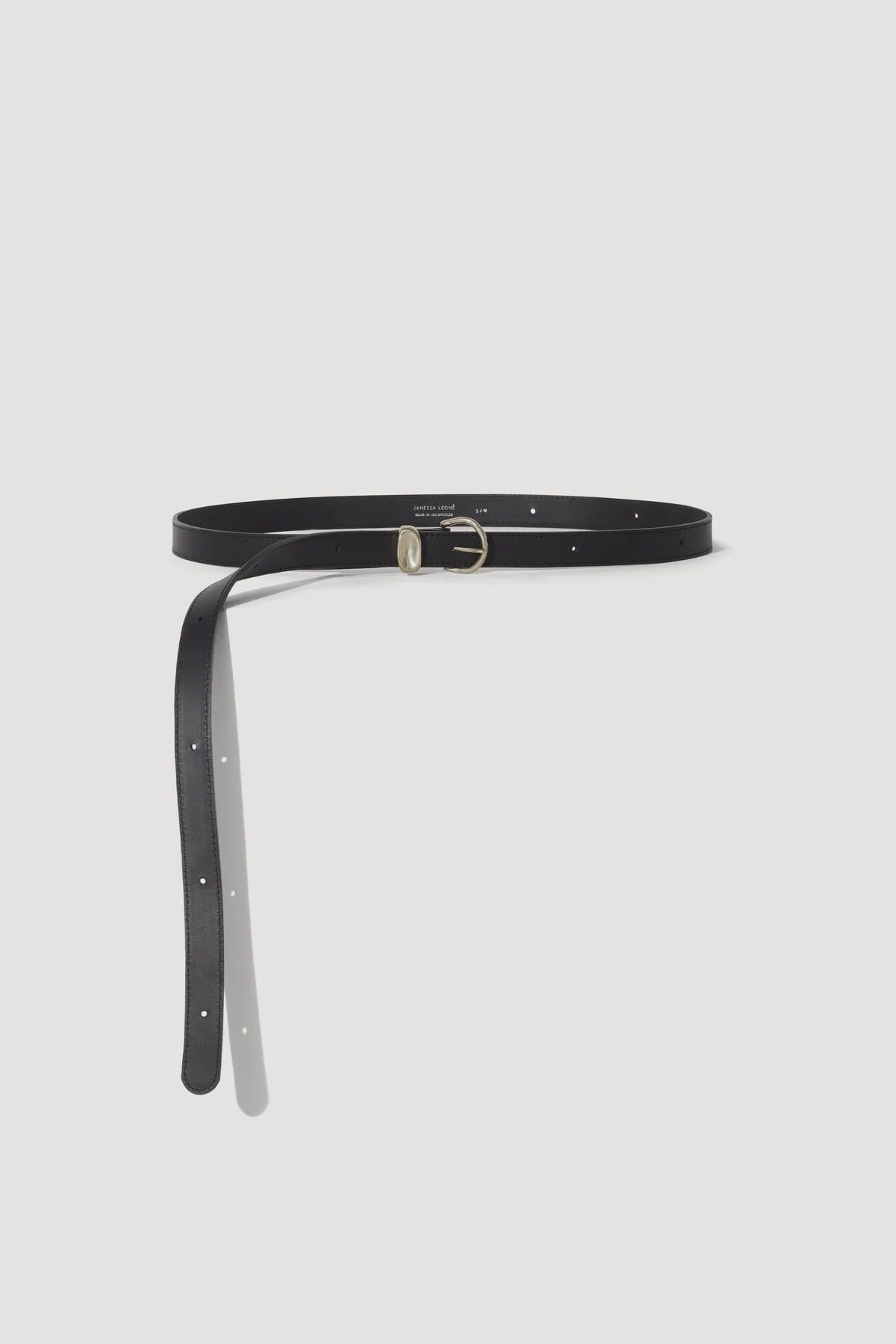 The Myra DW Belt by Janessa Leone is a slim, black regenerative leather piece with artisan silver hardware and a circular buckle. Elegantly double wrapped, it hangs with adjustable holes and is displayed against a plain white background for timeless style.