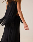 Natalie Martin Jessie Top in silk with fringe hem, sleeveless, modeled outdoors with windblown hair and outstretched arm.