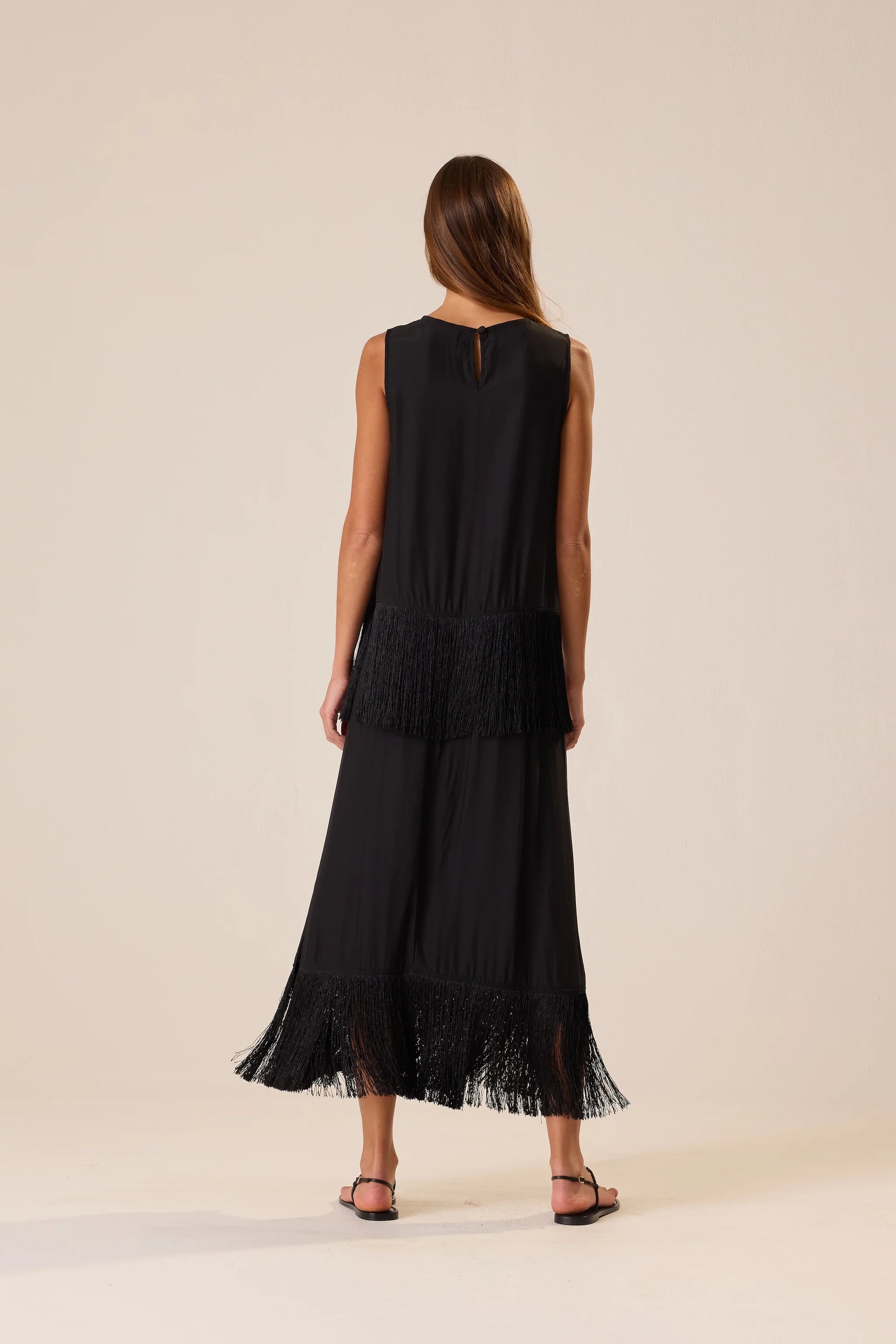 Natalie Martin Anita Skirt with fringe hem and side slit, shown from the back, styled with black sandals.