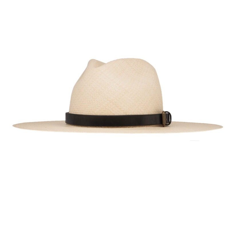 The Coda Hat by Ninakuru is a beige wide-brimmed toquilla straw hat with a black leather band and a subtle bronze buckle, set against a plain white background.