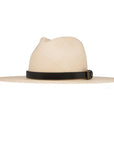 The Coda Hat by Ninakuru is a beige wide-brimmed toquilla straw hat with a black leather band and a subtle bronze buckle, set against a plain white background.