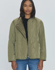 A woman with long, dark hair is standing against a plain, light background. She is wearing the Elva Onion Stitch Puffer Jacket by Pistola in military green over a black top and blue jeans, looking directly at the camera with a neutral expression.