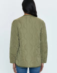 A person with long dark hair is seen from behind, wearing the Pistola Elva Onion Stitch Puffer Jacket in military green and blue jeans. The jacket showcases a simple, onion stitch quilting pattern against a plain, light gray backdrop.