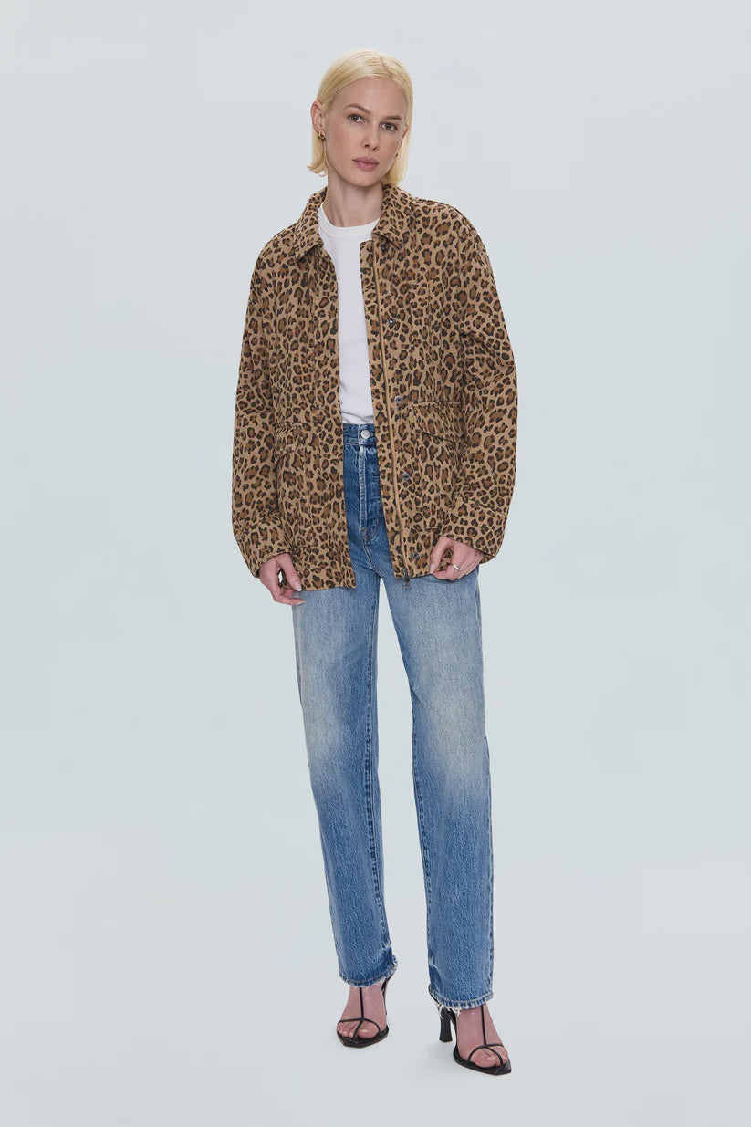 A woman with short blonde hair and a relaxed posture wears the Pistola Cecile Quilted Jacket in leopard print over a white T-shirt, with blue jeans and black heeled sandals against a plain background.