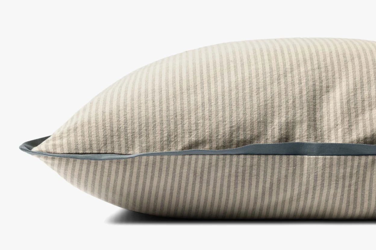 A close-up side view of the PJBR0001 Natural BB Pillow by Loloi Rugs, featuring beige and light gray stripes with blue piping, made from 100% cotton and a hidden zipper, shown on a plain white background.