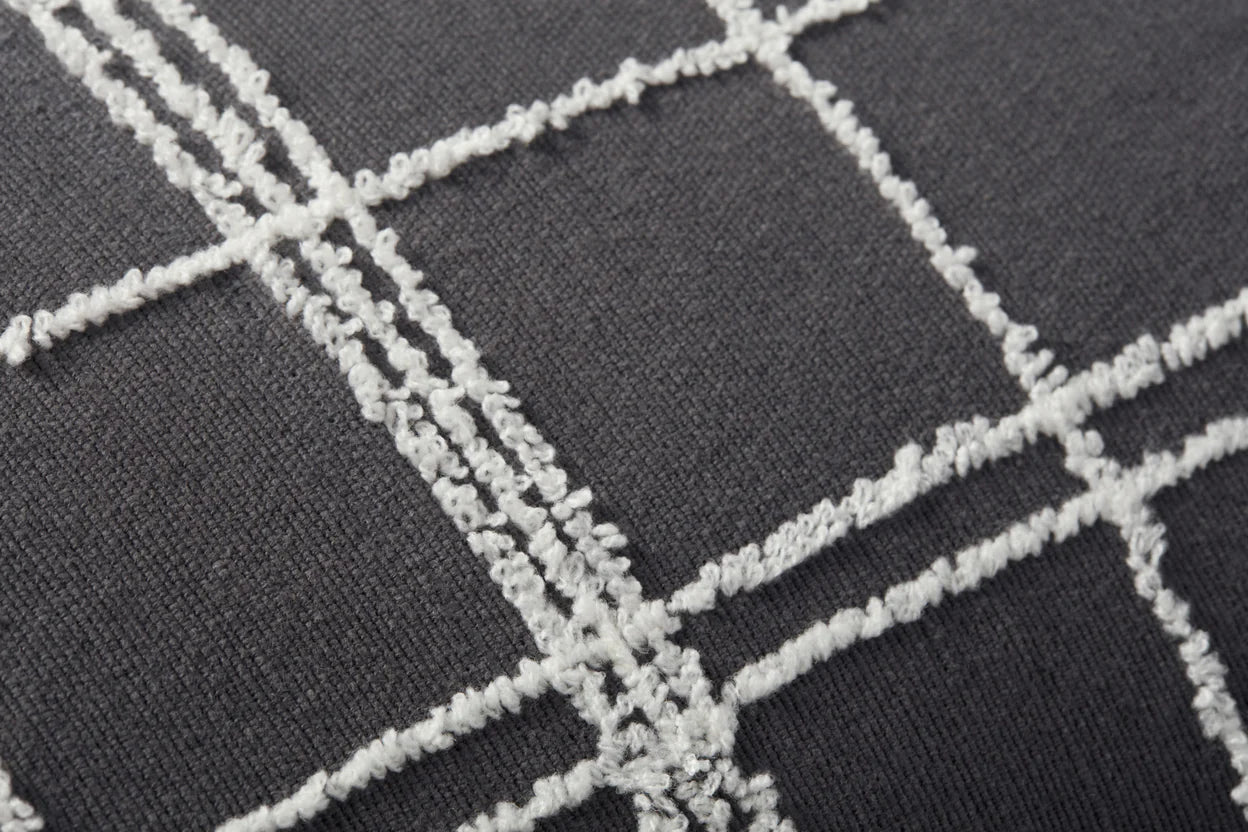 Close-up of the Loloi Rugs PJS0012 Graphite/Ivory Pillow 13x35, showing dark gray fabric with a textured white grid and knife edge finish, featuring raised intersecting lines for a simple, modern look.