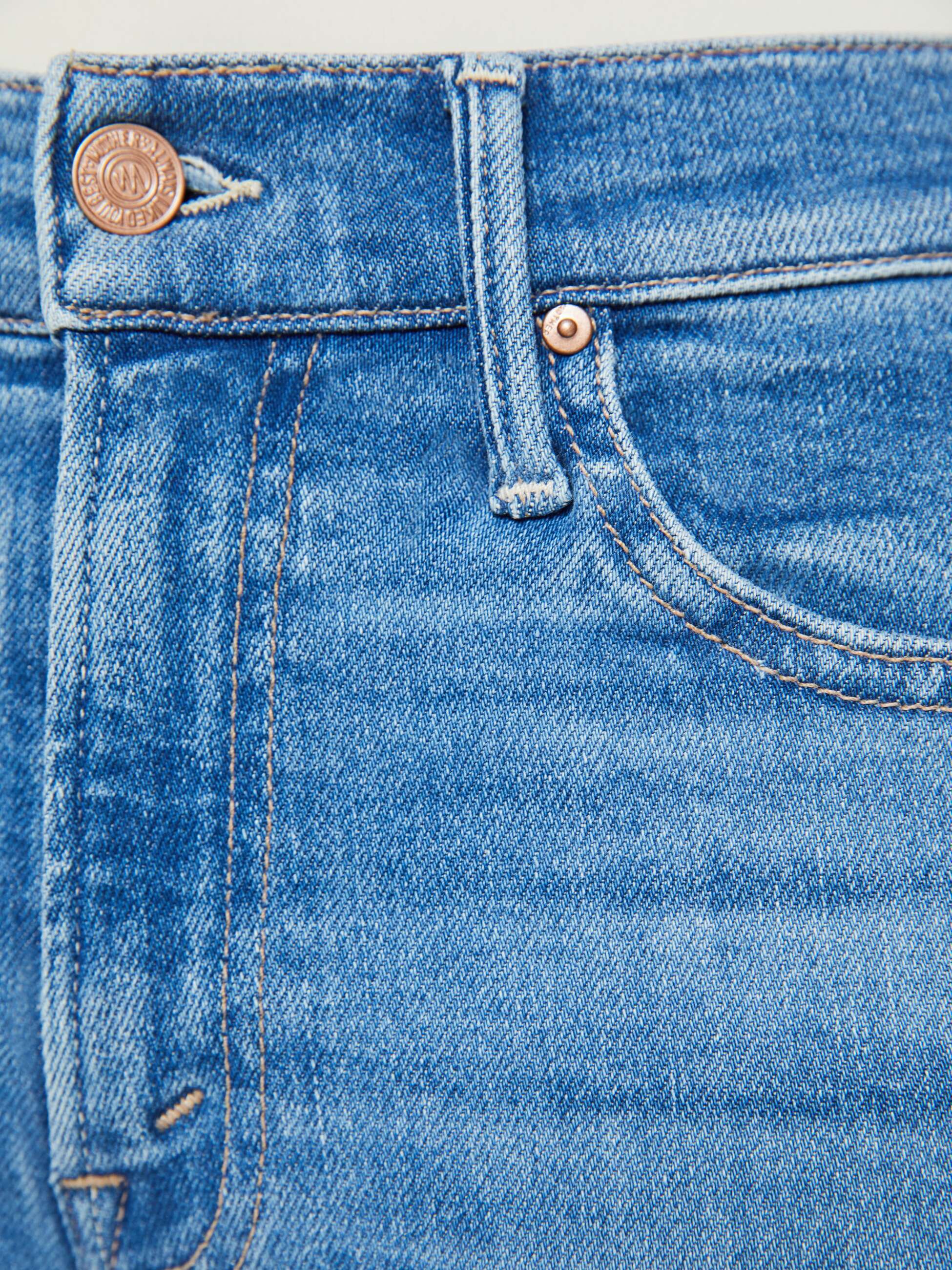 Close-up of the waistband and upper pocket of Mother’s Lil Insider Crop Step Fray jeans, featuring a metal button, belt loop, and copper rivet near the pocket corner.