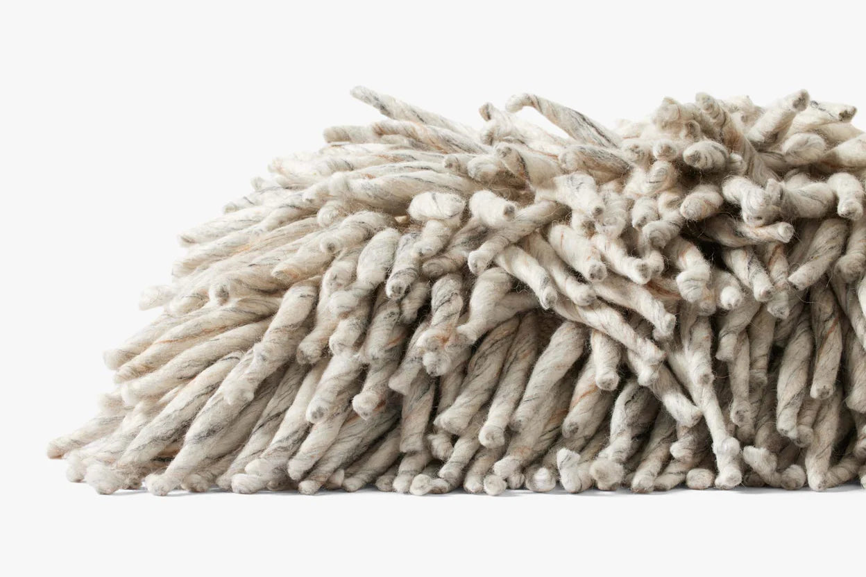 A close-up of the PLL0103 Silver Pillow 13x35 by Loloi Rugs, resting on a white background, showcases its durable cotton fibers and elegant, twisted texture.