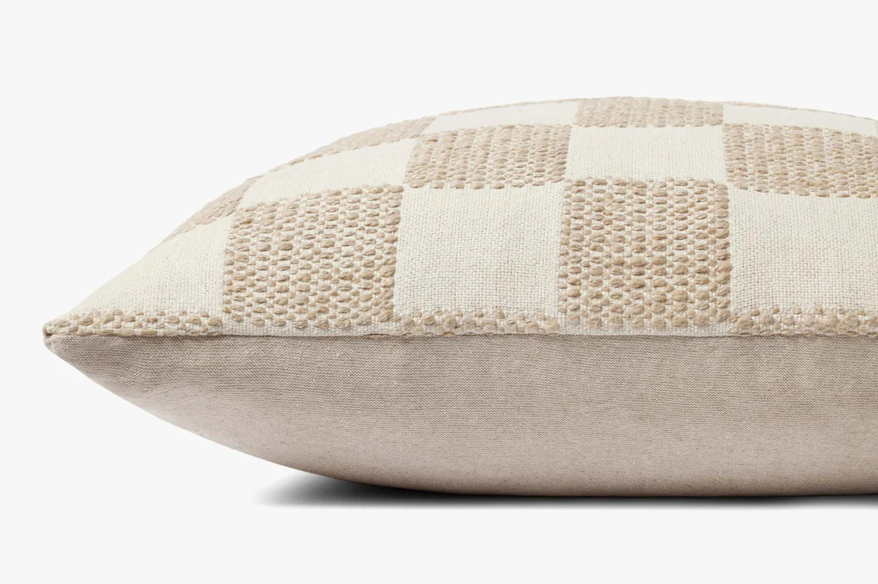 A close-up side view of the PLL0123 pillow 22x22 by Loloi Rugs, featuring a beige checkerboard design with woven and smooth fabric squares—an ideal accent for adding subtle style to modern living rooms.