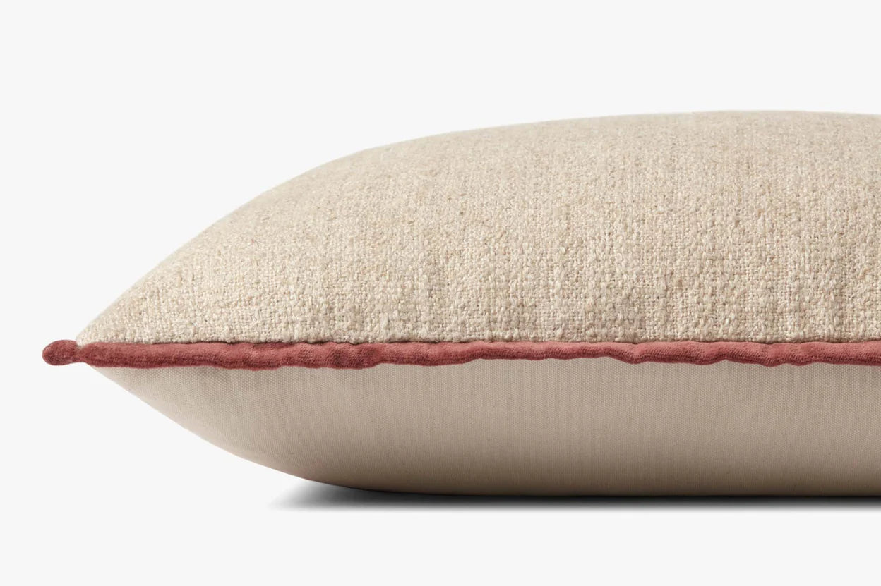 A close-up side view of the Loloi Rugs Aveline Ivory 16x26 pillow features a pinkish-red trim along the edge and a hidden flap zipper, set against a plain white background.
