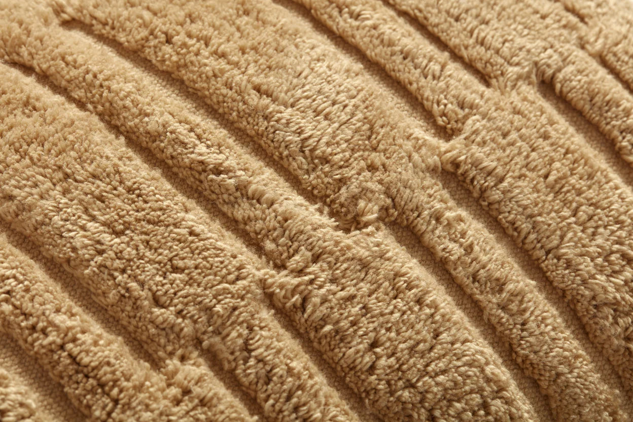 Close-up of the Arabella Wheat Pillow 16x26” by Loloi Rugs, featuring soft beige ribbed fabric with raised parallel lines that highlight its textured surface.