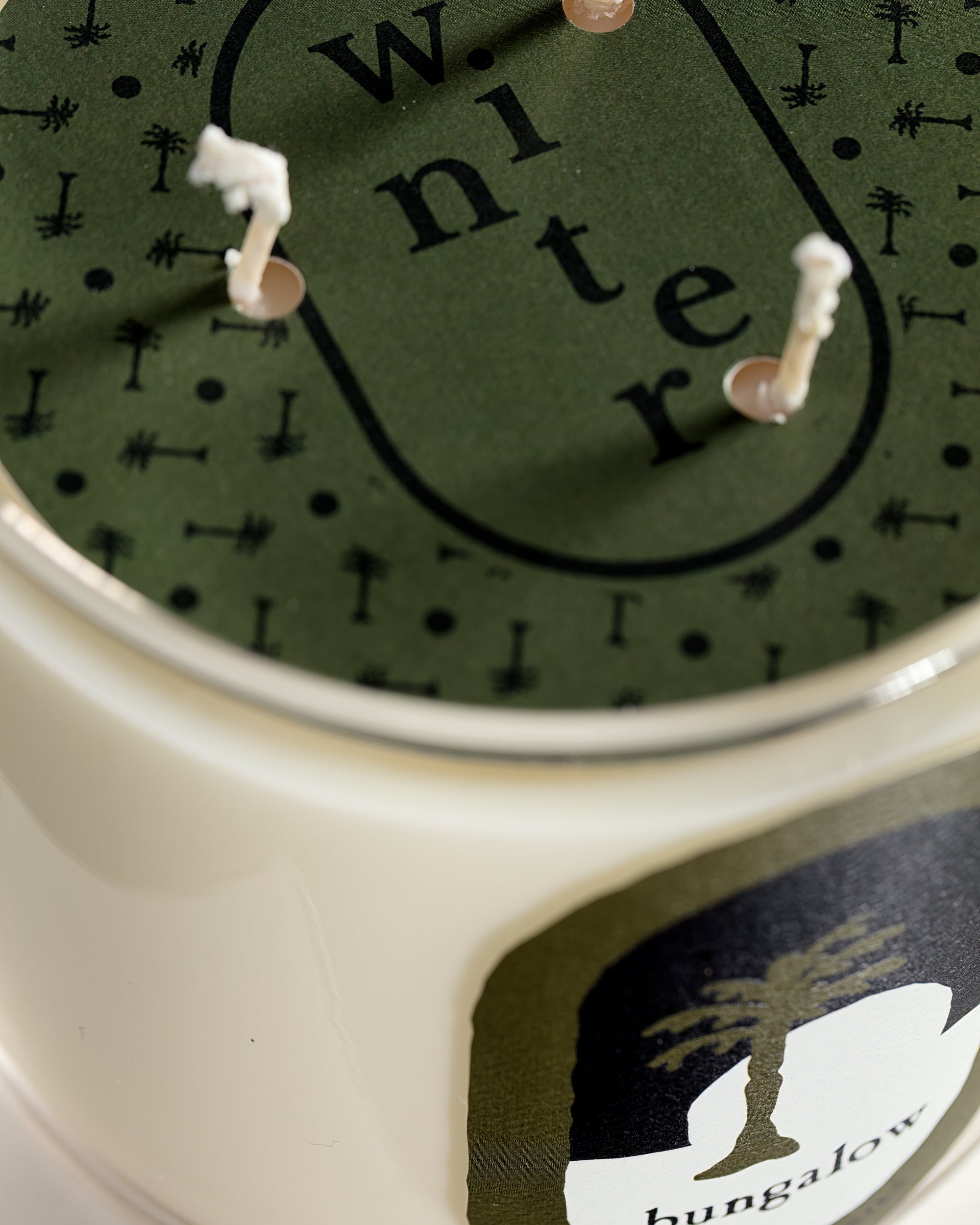 A close-up of Mame’s Signature Candle WINTER shows a green label and tree graphic on the jar, evoking the fresh balsam fir scent for the holidays.
