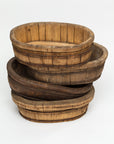 Three nested oval wooden baskets with a rustic appearance, showing natural textures and tones, placed on a white background in a Scottsdale Arizona bungalow by Indus Design Imports Oval Wood Bucket 10.