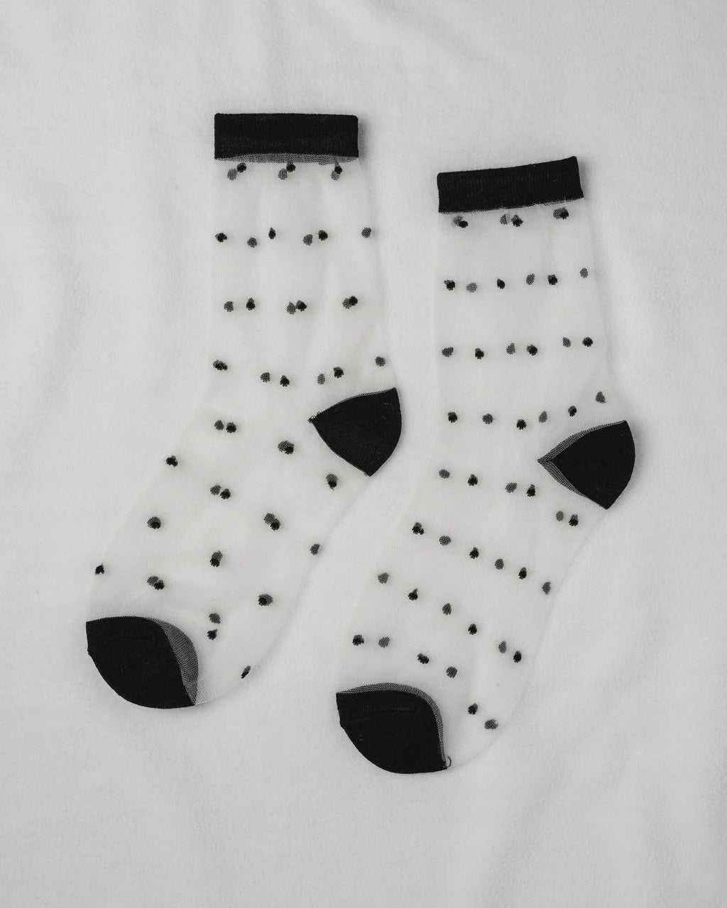Sheer Dot Socks by Unified: sheer white socks with small black dots and contrasting black cuffs, heels, and toes—an ideal playful touch for any outfit.