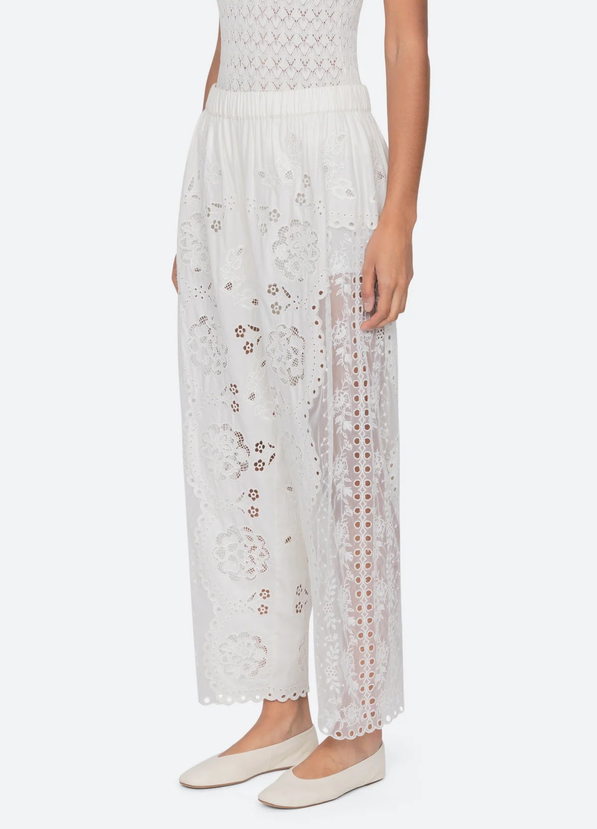 A person wearing Sea New York Gardener Pants paired with a white sleeveless top and white flat shoes.