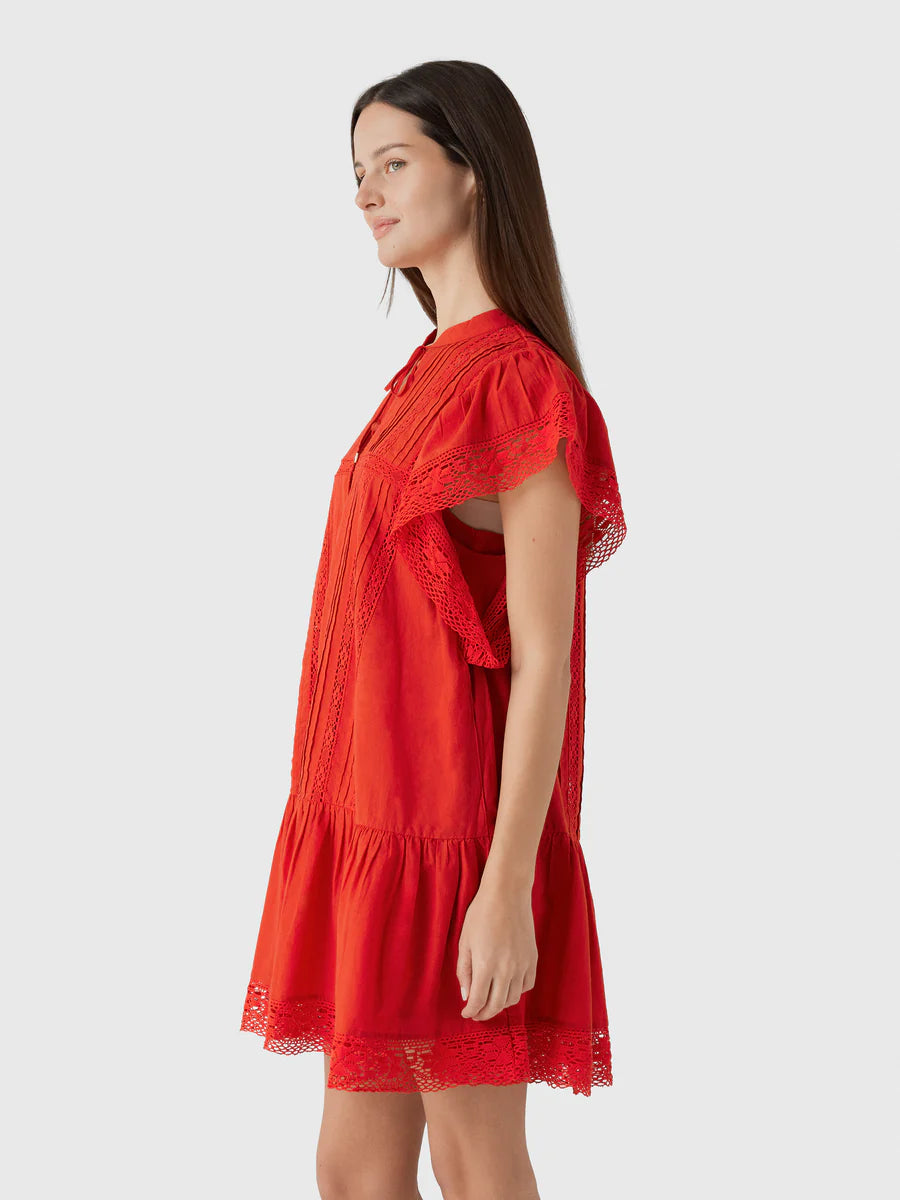 A woman with long brown hair wears the Pippa SS Mini Dress by Sea New York, a vintage-inspired red mini dress with lace accents, standing in profile against a plain light gray background.