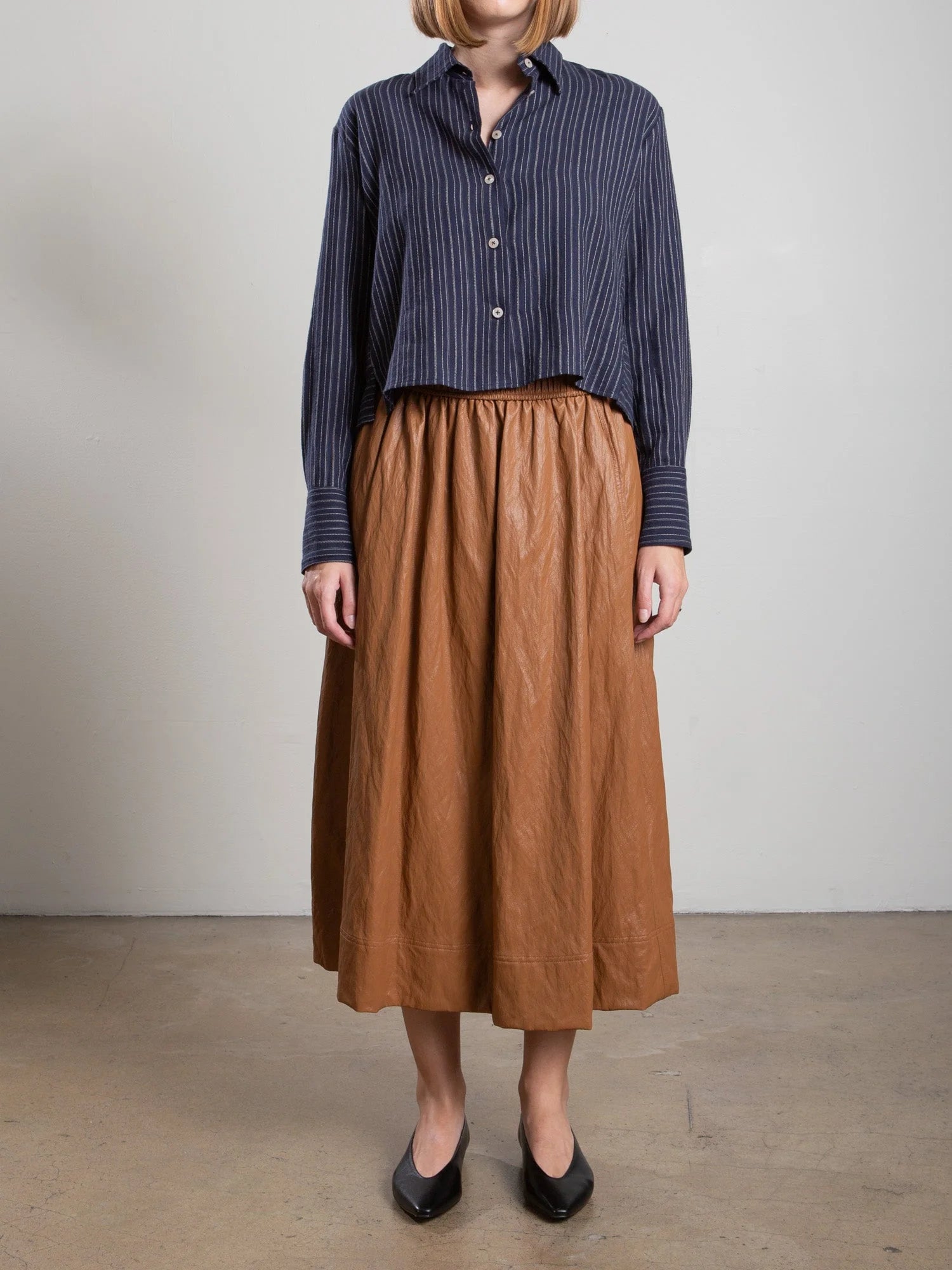 Pharaoh Claudia chestnut faux leather skirt with navy striped shirt, interior setting, Bungalow Furniture &amp; Accessories.