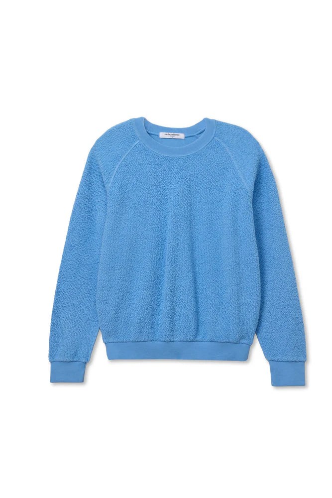 The Ziggy Reverse LS Sweatshirt by Perfectwhitetee is a light blue, shrunken-fit, long-sleeve cotton fleece crewneck with ribbed cuffs, collar, and hem, shown laid flat on a white background.
