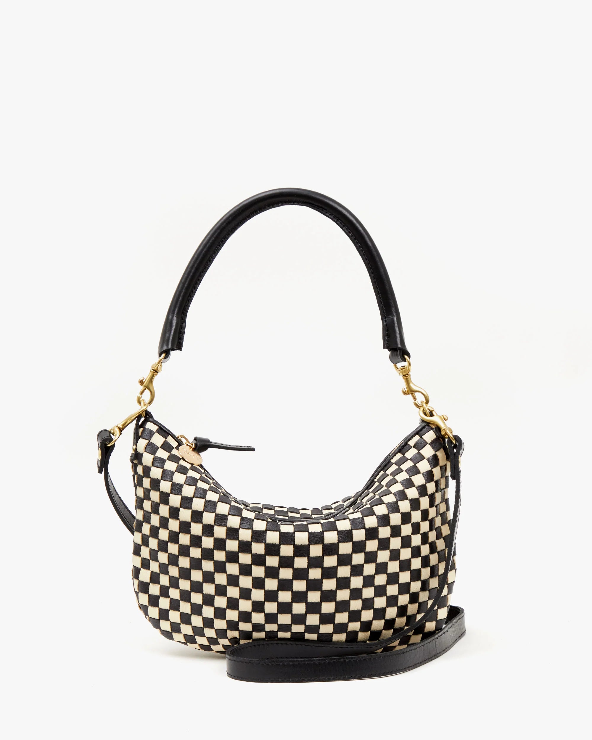 The Clare Vivier Petite Moyen is a stylish mini messenger bag with a crescent shape, featuring a black and beige checkered pattern, black handle, convenient crossbody straps, and gold hardware. It's elegantly showcased against a plain white background.