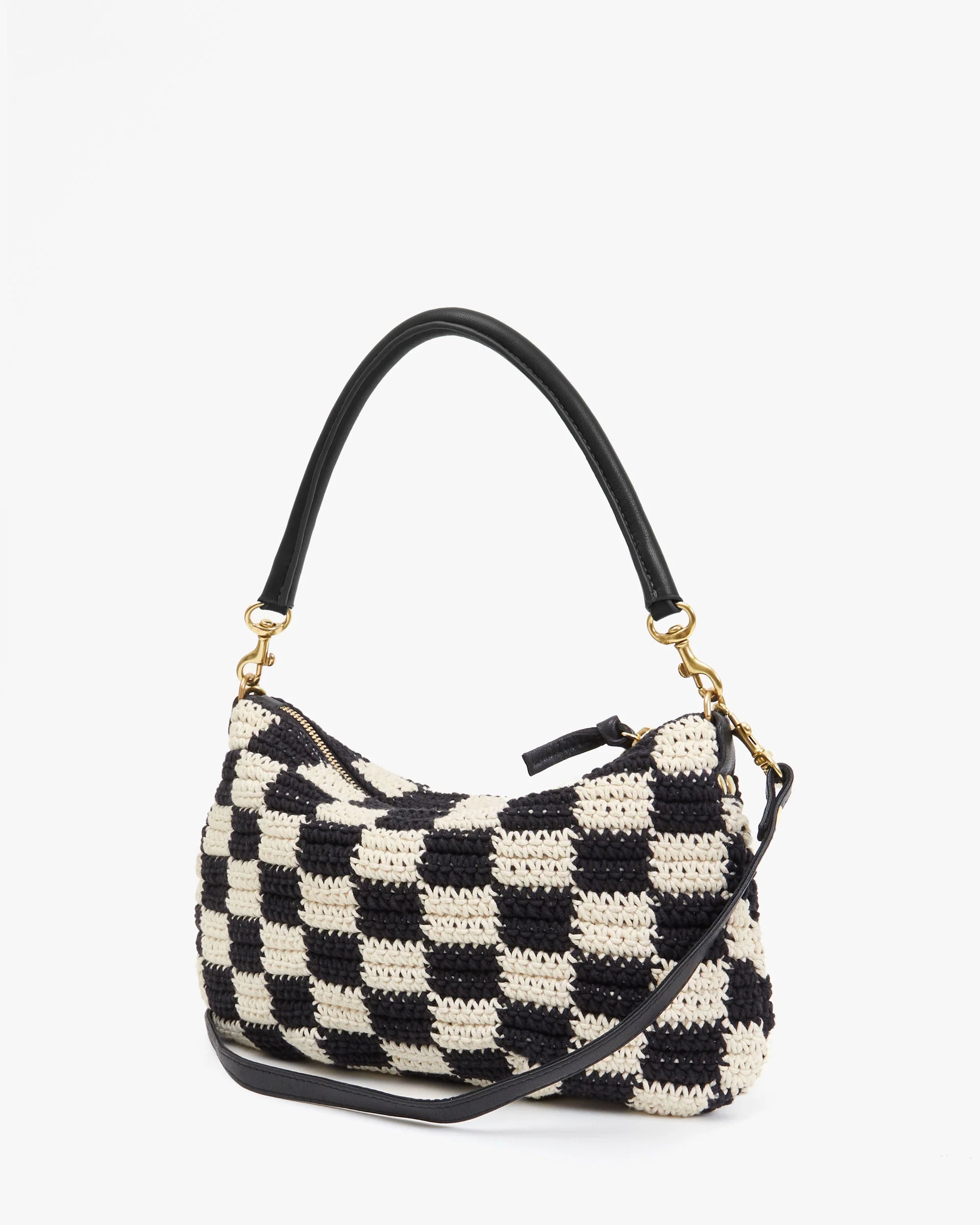 A black and white checkered crochet Petit Moyen Woven Checker shoulder bag from Clare Vivier with a black leather handle and gold hardware. The bag features a zip closure, handwoven leather details, and a detachable crossbody strap. The design creates a stylish, modern look.