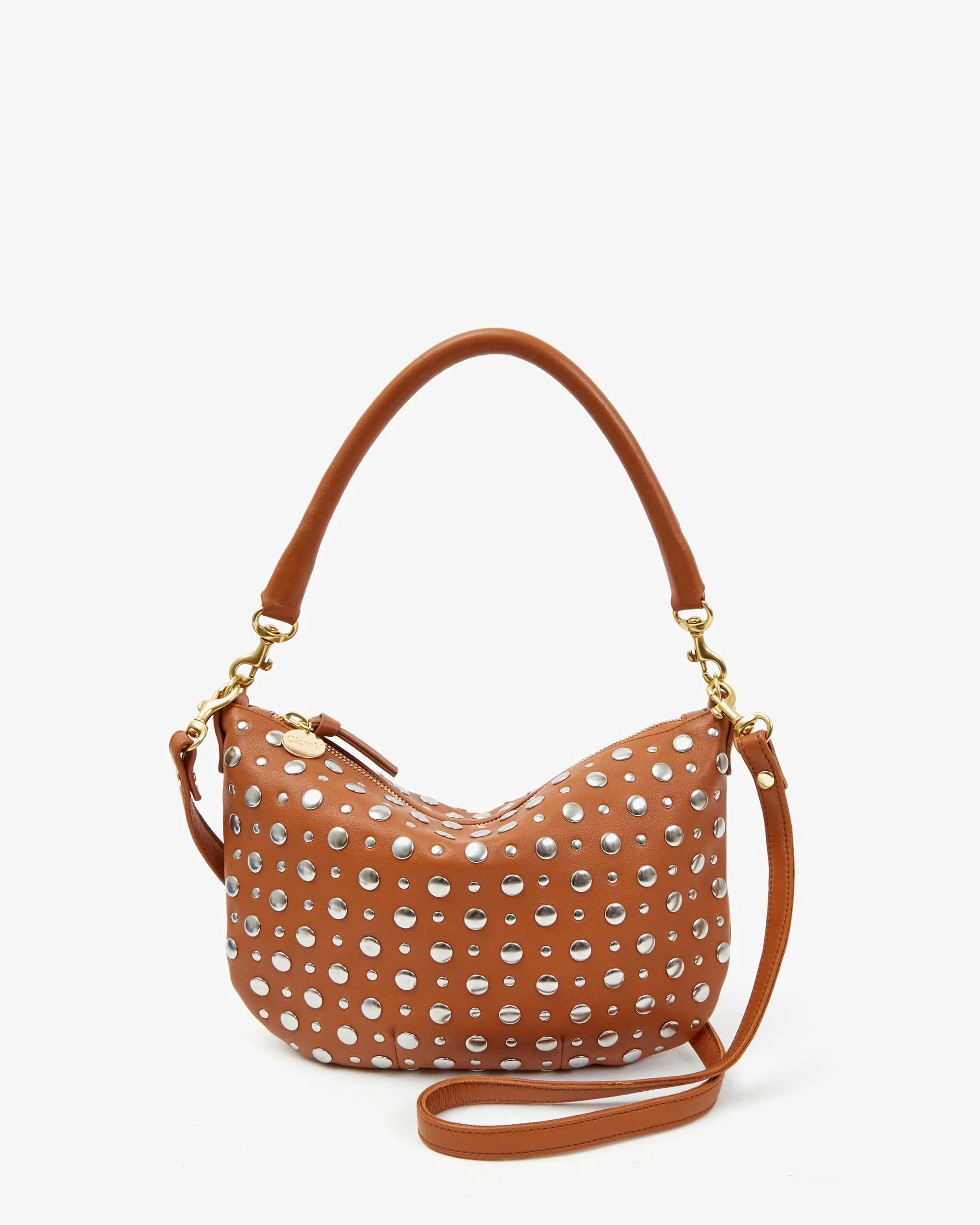 The Clare Vivier Petite Moyen is a small brown mini messenger handbag with silver studs, a short handle, detachable crossbody strap, and gold hardware like zipper pulls and strap clasps, presented against a white background.