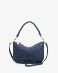 Featuring a suede finish, gold hardware, and chrome studs, the Petite Moyen handbag from Clare Vivier is a stylish navy blue woven accessory with a single top handle and a detachable crossbody strap. It boasts a secure zipper closure, all beautifully displayed against a plain white background.