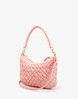 The Clare Vivier "Petite Moyen" is a pink handwoven leather handbag with gold-tone hardware, including hooks and a zipper. It has a short handle, detachable crossbody straps, and its woven texture gives it a stylish elegance against the white background.