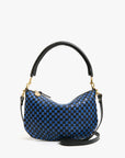 The Clare Vivier Petit Moyen Messenger S25 is a small, crescent-shaped mini messenger bag with a handwoven blue-and-black checkerboard leather pattern, gold hardware, a short black handle, and detachable crossbody straps.