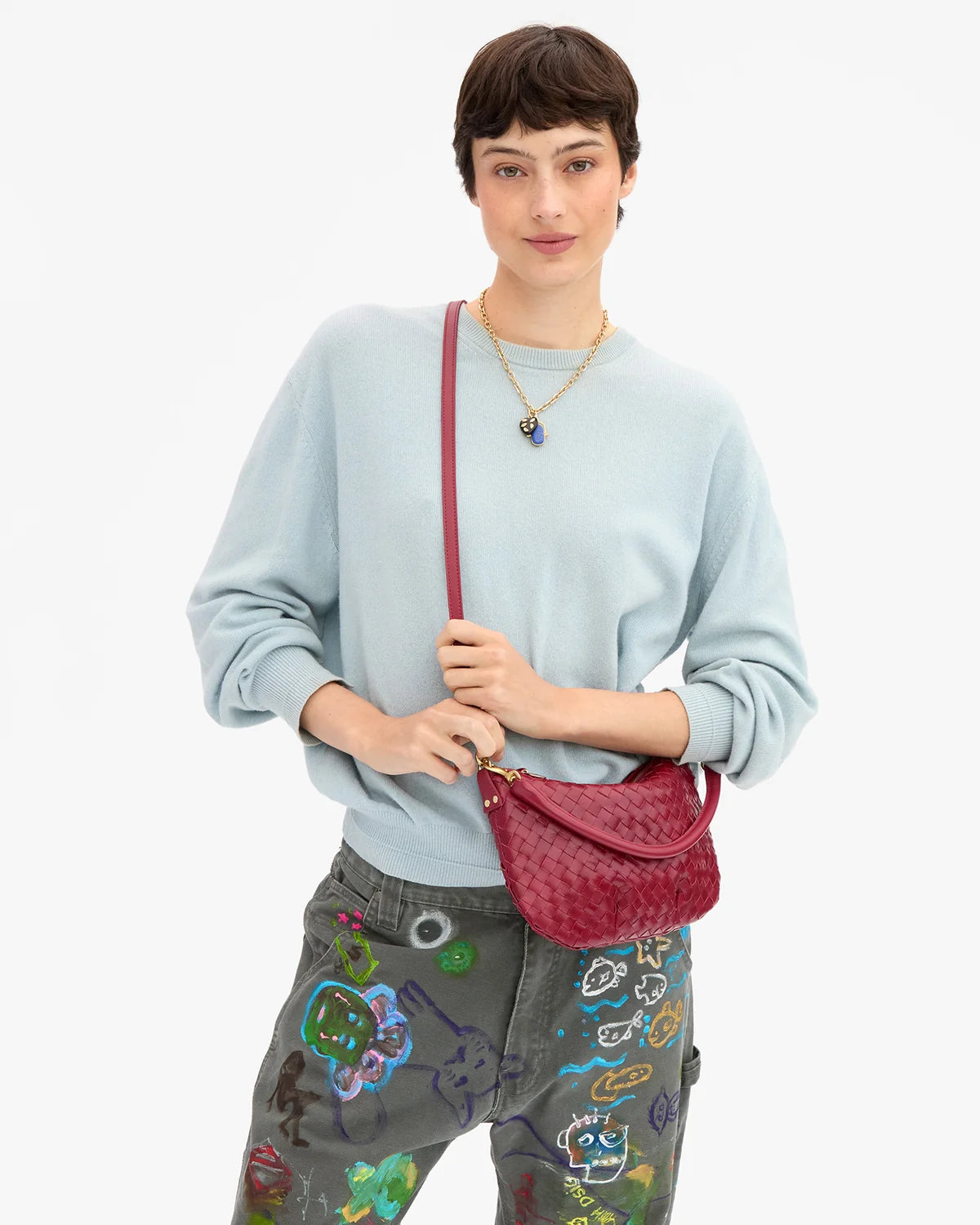 Clare Vivier Petit Moyen Messenger 26 in hand, styled with a light blue sweater and jeans, casual chic setting.