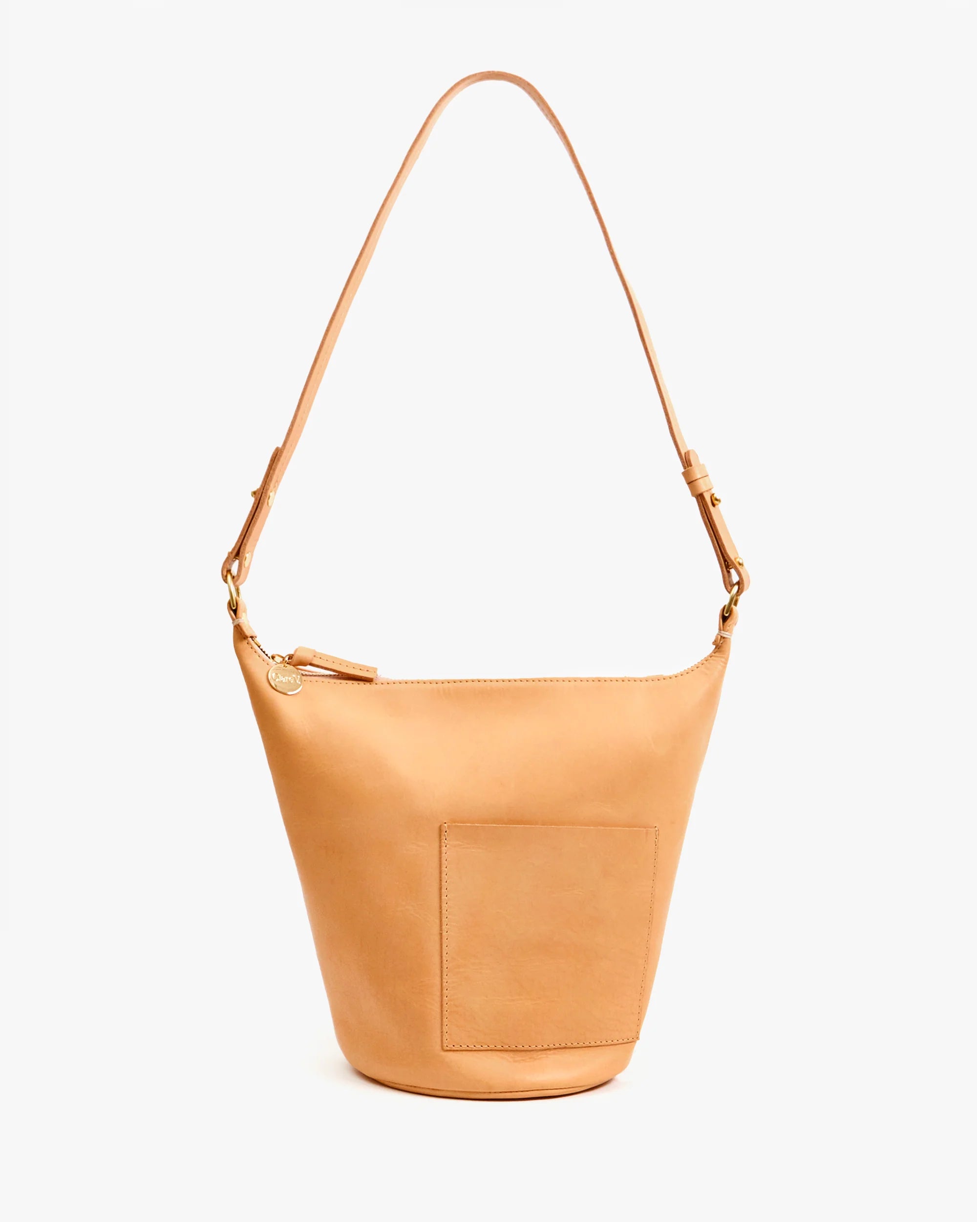 The Petit Jeanne by Clare Vivier is a tan handwoven leather bucket bag featuring a front pocket, zipper closure, and a single wide shoulder strap, displayed against a plain white background.