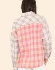 Shown from the back, the person wears the Xirena Phillipa Shirt—crafted from 100% cotton with light purple and pink plaid mismatched panels—paired with white pants for a relaxed style.