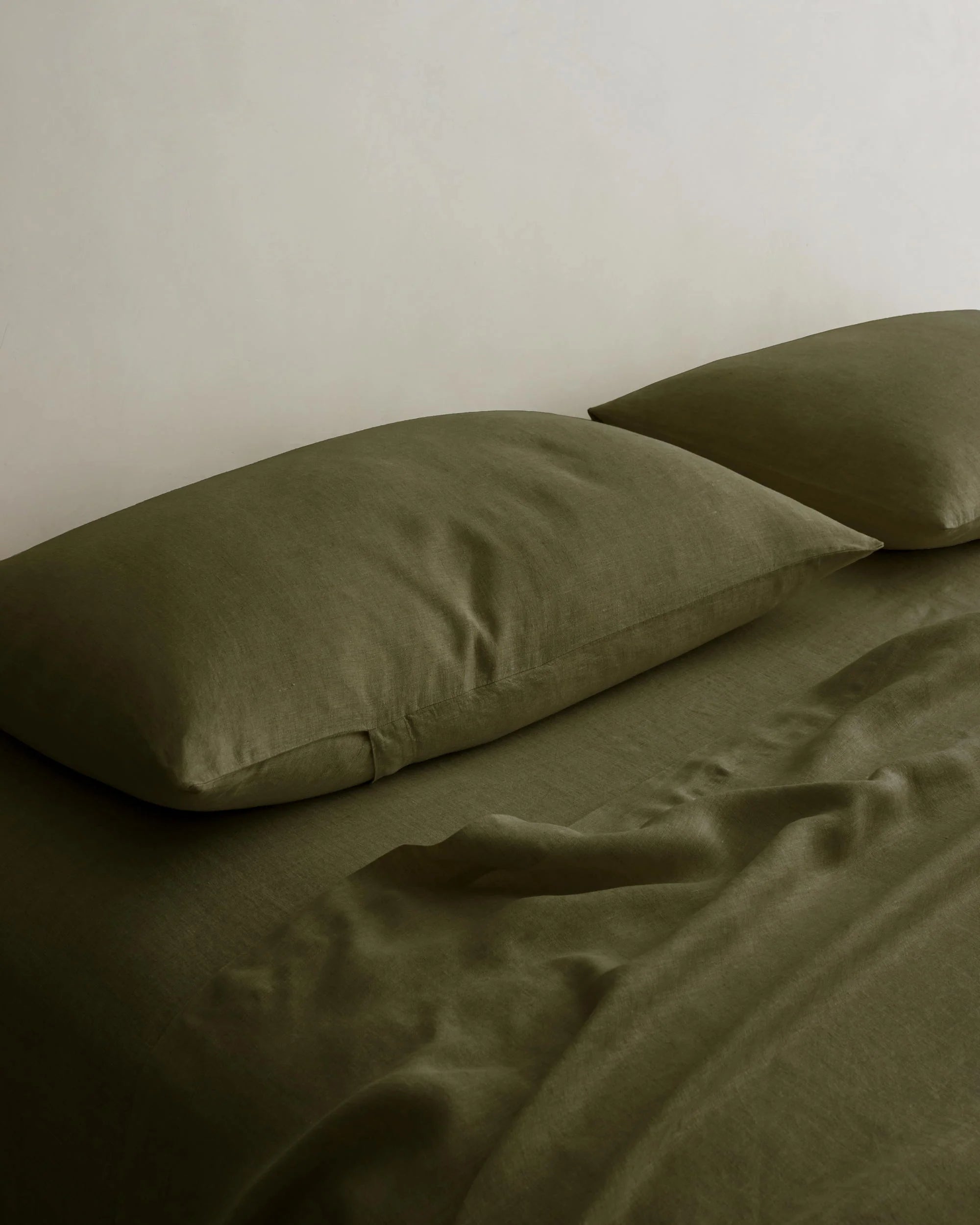 Linen pillowcases and sheet set by Cultiver Goods on a tidy bed in a minimalist bedroom setting.